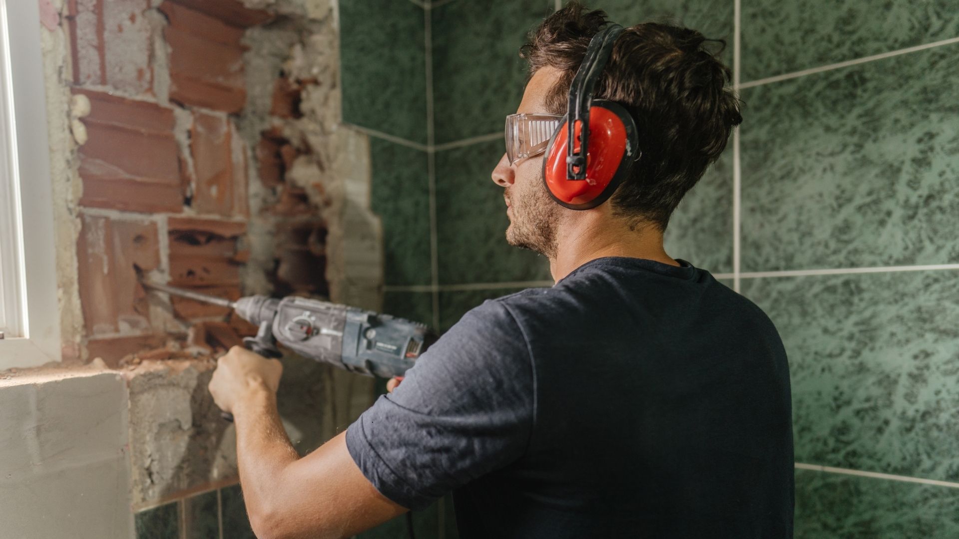man performing DIY tiling removal in bathroom